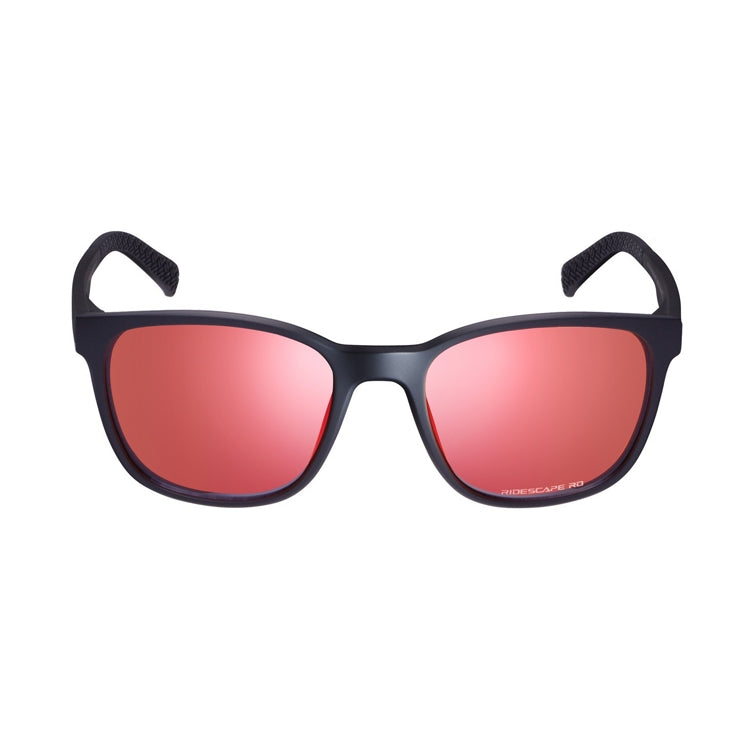 Matte black Shimano sunglasses with a lightweight full-rim frame and mirrored red-pink lenses, shown from front and side views on a light gray background. The rectangular lenses have gently rounded edges, while the slim black temples feature Shimano branding and textured temple tips for added grip. The reflective lenses display a vibrant rose-red finish with subtle purple tones around the lens edges.