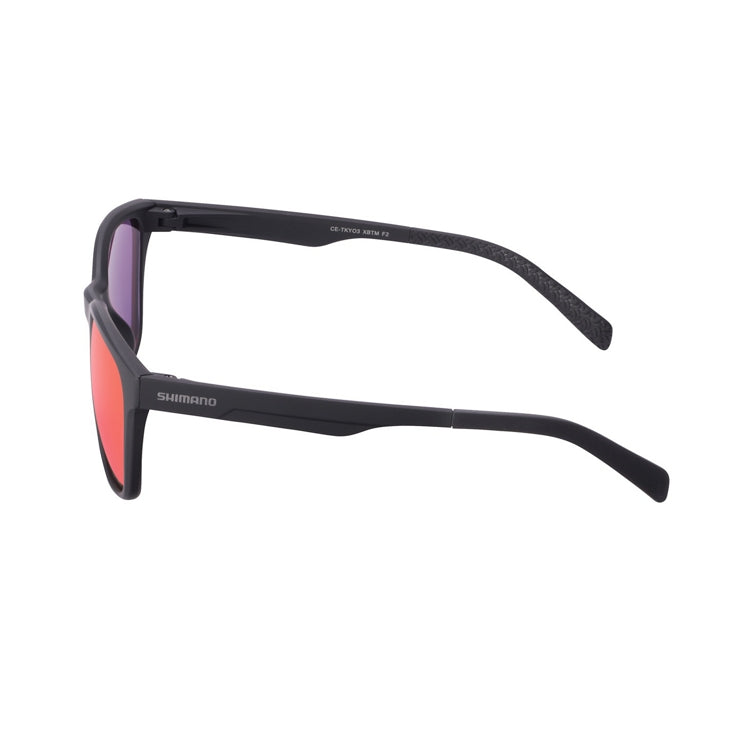 Matte black Shimano sunglasses with a lightweight full-rim frame and mirrored red-pink lenses, shown from front and side views on a light gray background. The rectangular lenses have gently rounded edges, while the slim black temples feature Shimano branding and textured temple tips for added grip. The reflective lenses display a vibrant rose-red finish with subtle purple tones around the lens edges.