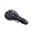Three-quarter front view of a black bicycle saddle showing the contoured shape, central channel, and metal rails underneath. The top surface displays a dark geometric graphic pattern with large lettering in contrasting gray tones. The saddle is positioned against a light gray background.