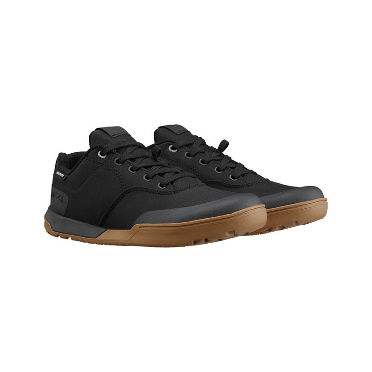 A pair of black shoes with black laces, tan sole, right view